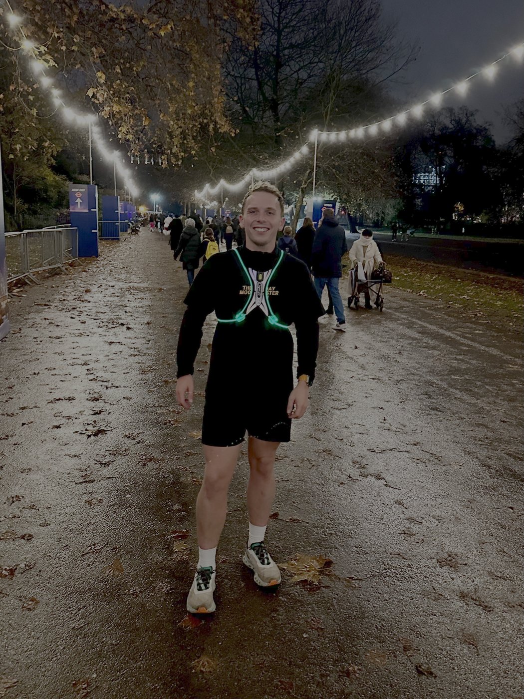 Charlie running at night through Hyde Park, lit by string lights