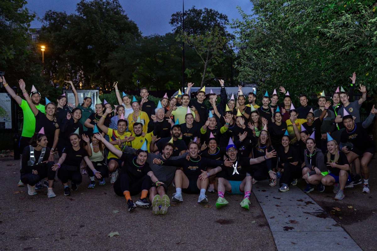 The Mood Booster Run Club celebrating together at night with party hats and glow sticks