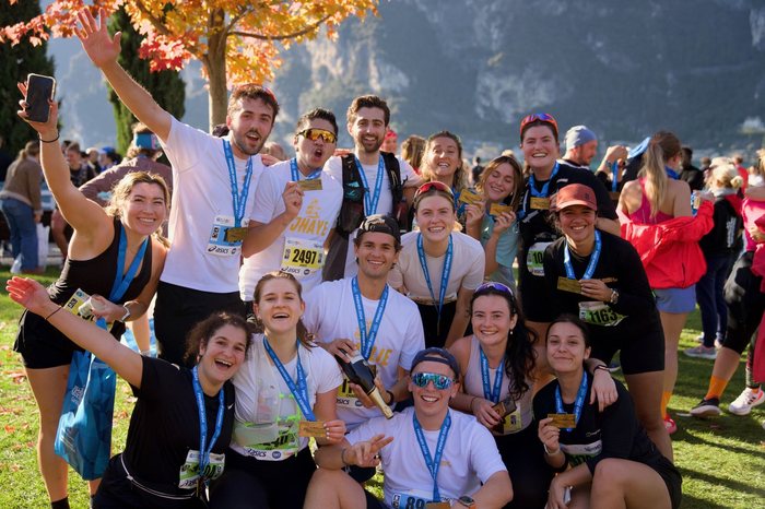 Group of runners celebrating with finisher medals by Lake Garda