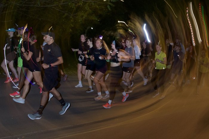 Long exposure night run through the park with glow sticks and light trails