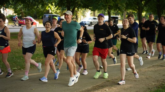 Runners laughing together on a sunny evening run through the park
