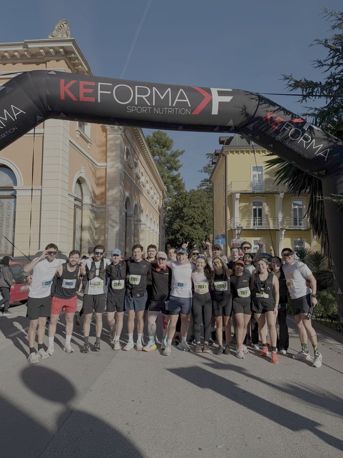The Mood Booster Run Club group photo under the finish arch at a marathon in Italy
