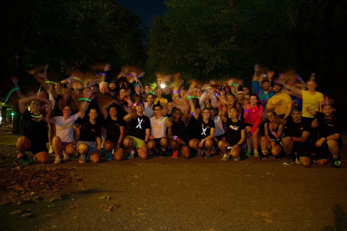 The Mood Booster Run Club celebrating a club birthday together at night with glow sticks and party hats
